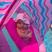 Izabella is registered to the contest to win money with this photo: baby, infant, pink, float, pool, water, hat, bow, swimming, child, outdoor, sunlight, colorful, striped, cute, relaxing, summer, portrait, closeup, fun