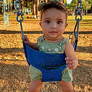 Carolina is registered to the contest to win money with this photo: baby, barefoot, bow, child, cute, daytime, fun, green_outfit, infant, outdoor, park, person, play, playground, smiling, summer, sunlight, swing, trees, woodchips