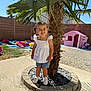 Juliette participe au concours pour gagner de l'argent avec cette photo : child, girl, smiling, outdoor, palm_tree, playground, playhouse, sunny, daytime, grass, fence, shorts, white_shirt, shoes, pigtails, happy, shadow, concrete, garden, nature