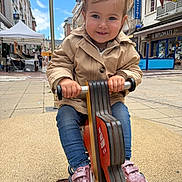Juliette participe au concours pour gagner de l'argent avec cette photo : child, toddler, playground, spring_rocker, pink_shoes, pony_tails, jacket, jeans, outdoor, urban, street, buildings, sky, daytime, smiling, toy, person, fun, play, happy