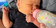 Renee is registered to the contest to win money with this photo: baby, newborn, bottle, feeding, black_onesie, arrow_pattern, blanket, gray_blanket, hand, arm, infant, sleeping, closeup, skin, person, baby_bottle, pink_cap, resting, cozy, indoor