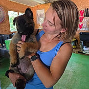 Balthazar a rejoint le concours — aidez-le/la à gagner de superbes lots ! woman, puppy, dog, indoor, holding, smile, blue_tank_top, short_hair, watch, green_floor, wooden_wall, window, pet, happy, tongue_out, casual, person, animal, cute, playful