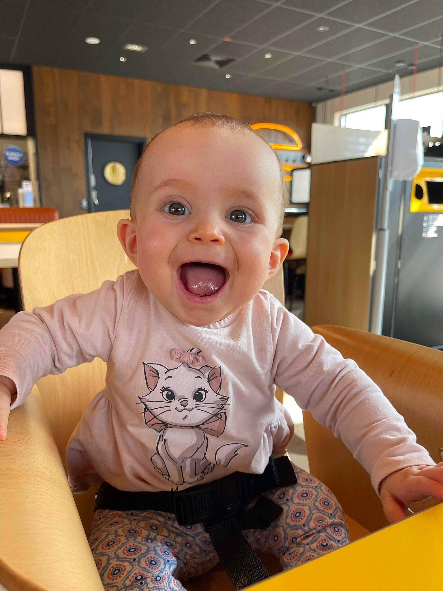 Arya a rejoint le concours — aidez-le/la à gagner de superbes lots ! arm, baby, baby_laughing, baby_toddler_clothing, chair, cheek, child, comfort, floor, flooring, fun, happy, person, room, sitting, sleeve, smile, t_shirt, table, toddler