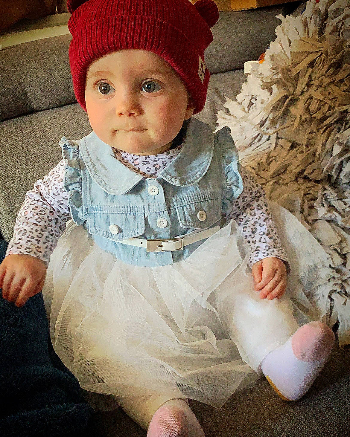 Arya participe au concours pour gagner de l'argent avec cette photo : baby, baby_toddler_clothing, cap, costume_hat, dress, eye, face, fashion_accessory, headgear, headwear, knit_cap, linens, outerwear, pattern, person, sitting, sleeve, textile, toddler, white