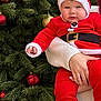 Yanis participe au concours pour gagner de l'argent avec cette photo : baby, infant, santa_costume, santa_hat, christmas_tree, ornament, bauble, red_clothing, blue_shoes, hand, adult_hand, pine_needles, festive, holiday, decoration, portrait, cute, evergreen, seasonal, gold_bauble