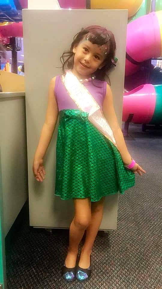 Maliyah is registered to the contest to win money with this photo: child, child_model, clothing, cocktail_dress, dress, footwear, fun, girl, green, hair, human_hair_color, joint, joy, leg, person, pink, purple, shoulder, standing, textile