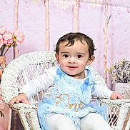 Raelynn joined the competition — help win amazing prizes! toddler, child, wicker_chair, blue_dress, lace, white_clothing, pink_flowers, vase, indoor, portrait, smiling, curly_hair, decor, plant, soft_lighting, cute, seated, baby, fabric, face