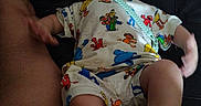Mateo is registered to the contest to win money with this photo: baby, pacifier, infant, pajamas, blanket, adult, torso, skin, foot, hand, lying_down, indoors, clothing, person, child, cute, toddler, colorful, pattern, comfort