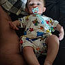 baby, pacifier, infant, pajamas, blanket, adult, torso, skin, foot, hand, lying_down, indoors, clothing, person, child, cute, toddler, colorful, pattern, comfort