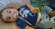 Mateo joined the competition — help win amazing prizes! baby, pacifier, toy, blue_shirt, cartoon_character, pants, sailboat_pattern, blanket, lying_down, infant, child, cute, indoors, comfort, soft_surface, playful, colorful, hand, face, sleepwear