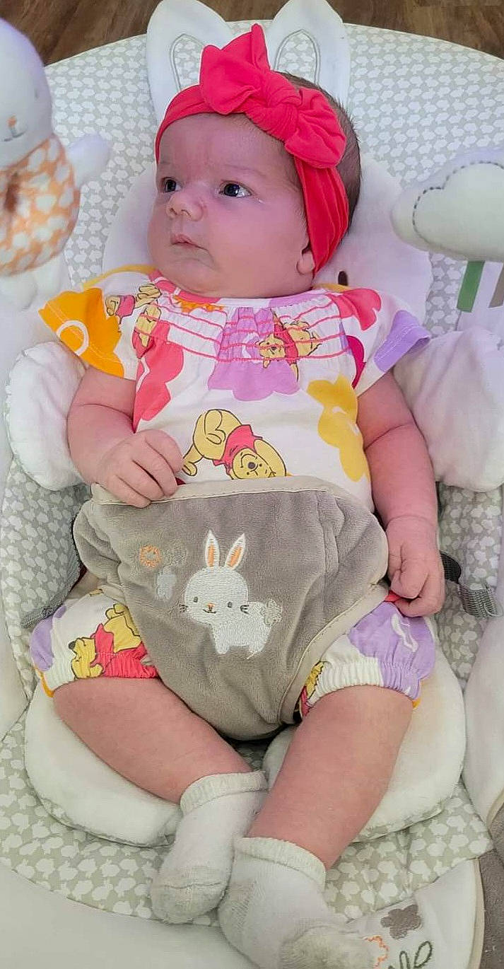 Elliana is registered to the contest to win money with this photo: baby, baby_toddler_clothing, cheek, child, comfort, dress, face, glasses, head, headwear, human_body, leg, person, pink, sitting, skin, sleeve, textile, thigh, toddler