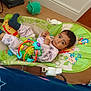 Yug Sanskar Ahuja is registered to the contest to win money with this photo: baby, child, baby_rocker, toy, snack, floor, wooden_floor, indoor, clothing, socks, animal_print, green, colorful, furniture, face, person, cute, relaxing, home, infant
