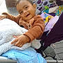 Yug Sanskar Ahuja is registered to the contest to win money with this photo: toddler, child, stroller, blanket, cozy_clothing, pointing, happy, smiling, outdoor, pavement, toy, knitwear, colorful, patterned, baby, person, playful, seat, fabric, warm