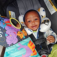 Legend joined the competition — help win amazing prizes! baby, car_seat, child, smiling, hood, neck_pillow, toy, book, colorful, clothing, seatbelt, infant, cute, happy, indoor, person, face, playful, cozy, safe