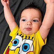 Harlie is registered to the contest to win money with this photo: arms_up, baby, background, blue_eyes, cartoon_character, child, clothing, cute, expression, face, hair_spikes, indoor, infant, lying_down, person, playful, portrait, spongebob, tongue_out, yellow_shirt