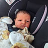 newborn, baby, car_seat, blanket, mittens, face, infant, child, clothing, cushion, closeup, portrait, indoor, seatbelt, safety, head_support, soft, cute, sleepy, resting
