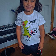 Ryder is registered to the contest to win money with this photo: casual, child, dinosaur, door, floor, hair, happy, indoor, keyboard, person, playful, room, shoes, shorts, smiling, standing, toy, tshirt, wig, young