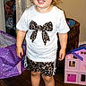 Raya joined the competition — help win amazing prizes! toddler, child, indoor, smiling, curly_hair, blue_eyes, white_shirt, leopard_print, shorts, sandals, toy_car, dollhouse, wooden_floor, basket, curtain, happy, standing, playtime, person, home