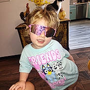 Raya joined the competition — help win amazing prizes! toddler, child, sunglasses, pink, cartoon_tshirt, indoor, cat, black_and_white_cat, wooden_floor, kitchen, cabinet, flower_vase, yellow_flowers, hand, person, smiling, curly_hair, home_interior, furniture, decorative_rooster
