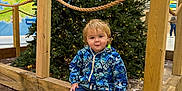 Tommy joined the competition — help win amazing prizes! toddler, child, christmas_tree, red_boots, blue_jacket, smiling, indoor, public_space, wooden_fence, marble_floor, holiday_decor, festive, casual_clothing, small_child, curly_hair, seated, happy, cute, lighting, portrait