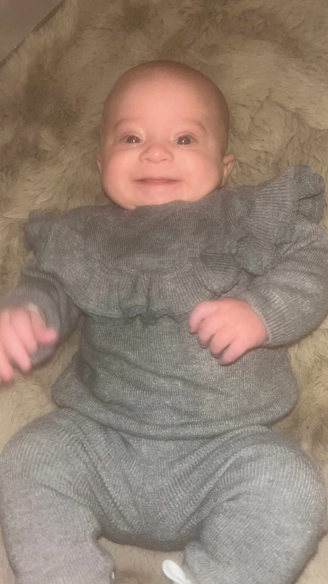 Soline a rejoint le concours — aidez-le/la à gagner de superbes lots ! baby, infant, smiling, portrait, one_person, face, bald_head, chubby_cheeks, gray_outfit, ruffled_sweater, hands, legs, blanket, fur_blanket, cozy, soft_texture, indoor, close_up, happy, lying_down