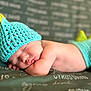 baby, sleeping, crocheted_hat, crocheted_shorts, dinosaur_costume, green_blanket, text, infant, cute, peaceful, soft_skin, closeup, resting, headwear, cozy, child, portrait, indoor, newborn, cute_costume