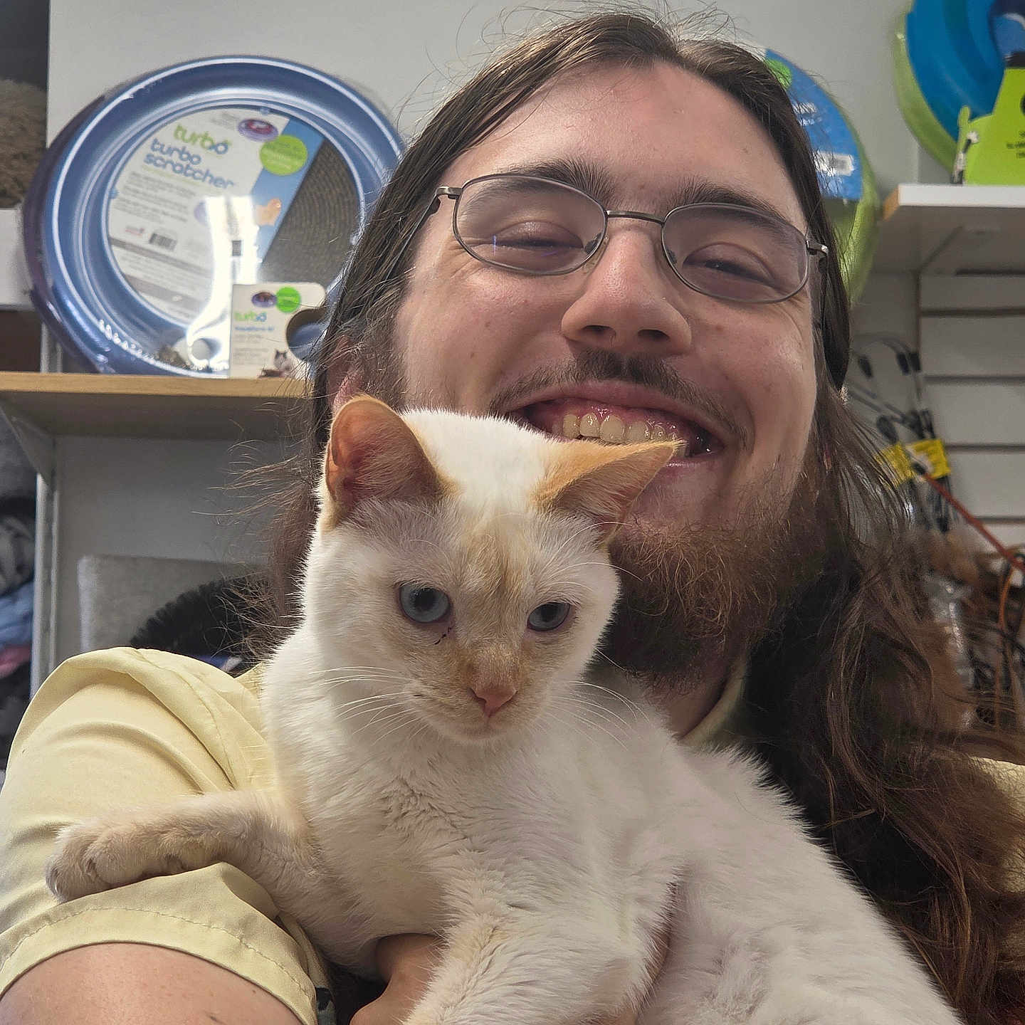 Biscuit joined the competition — help win amazing prizes! animal, beard, casual, cat, closeup, cute, feline, friendly, glasses, happy, holding, indoor, long_hair, person, pet_products, pet_store, portrait, shelf, smiling, white_cat