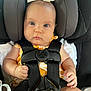 baby, car_seat, graco, child, infant, seatbelt, straps, yellow_clothing, bow, face, hands, cute, secure, car_interior, young_child, sitting, looking_at_camera, blue_eyes, head_support, closeup