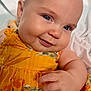 Vivian is registered to the contest to win money with this photo: baby, child, smile, blue_eyes, yellow_dress, floral_pattern, close_up, cheek, hand, skin, infant, cute, portrait, soft_light, blanket, happy, indoors, person, young, face