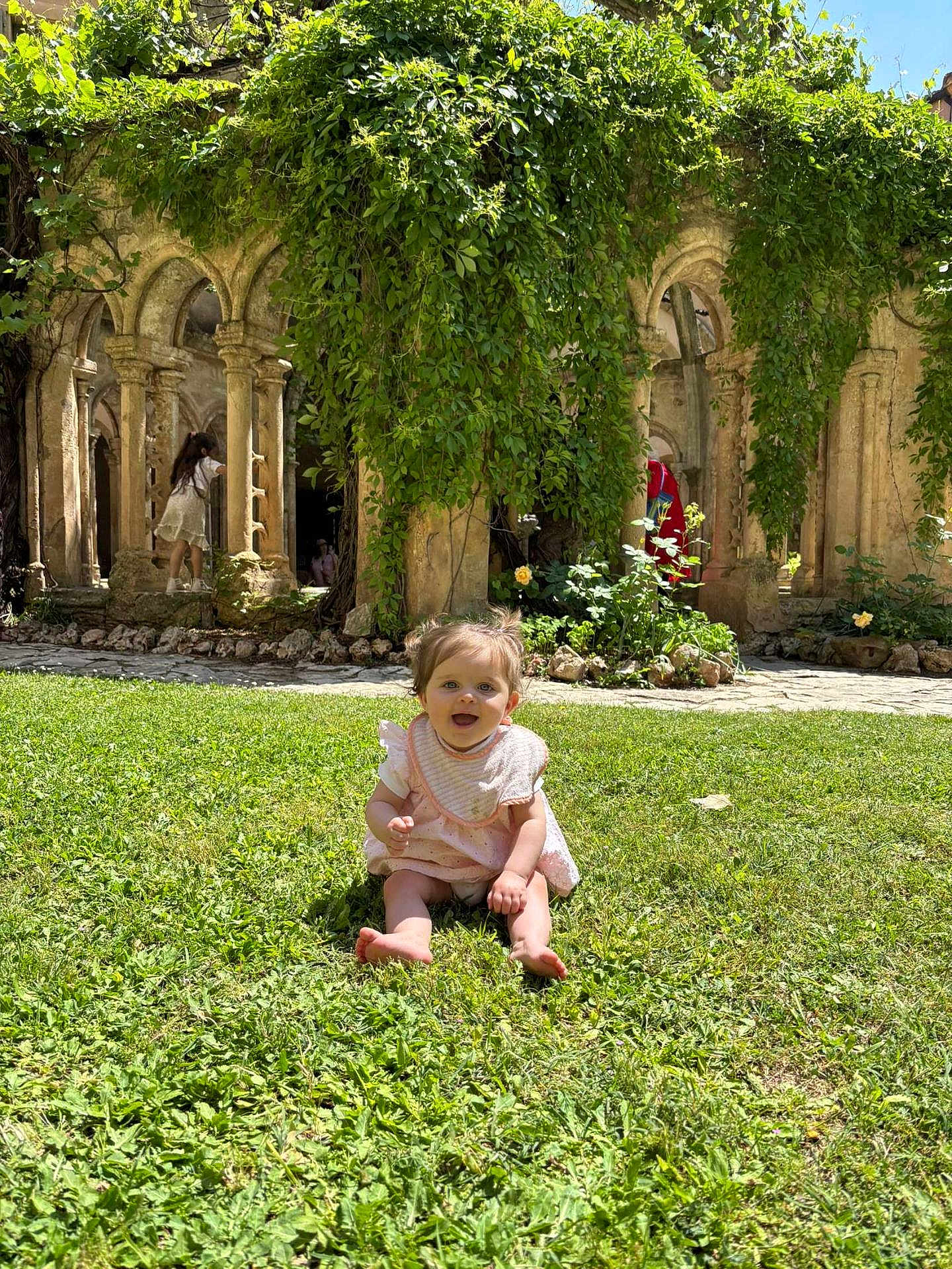 Milady participe au concours pour gagner de l'argent avec cette photo : baby, child, grass, greenery, stone_arches, ancient_structure, sunlight, outdoor, playful, happy, smiling, nature, garden, plants, architecture, historic, person, toddler, daylight, exploration