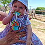 Milady participe au concours pour gagner de l'argent avec cette photo : baby, child, outdoor, sun_hat, floral_dress, toy_keys, hand, smiling, face, person, nature, tree, fence, daylight, playing, cute, holding, chewing, summer, happy