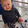 Eden participe au concours pour gagner de l'argent avec cette photo : toddler, child, baby, smiling, blue_eyes, sitting, indoors, bed, blanket, clothing, black_shirt, patterned_pants, socks, happy, curtains, natural_light, face, hand, footwear, portrait