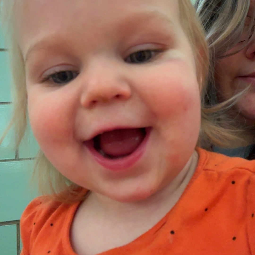 Noelle is registered to the contest to win money with this photo: applique, baby, babylaughing, blonde, bodypart, clothing, face, hair, happy, head, laughing, mouth, person, photography, portrait, selfie, shirt, smile, t_shirt, teeth