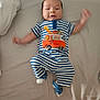 baby, infant, child, striped_clothing, blue, white, orange, bed, blanket, socks, motion_blur, lying_down, cute, smiling, apparel, animal_applique, giraffe, car, indoor, person
