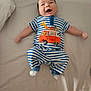 Lucas is registered to the contest to win money with this photo: baby, infant, smiling, striped_clothing, blue_and_white, bed, lying_down, happy, cute, child, socks, animal_design, giraffe, bus, orange, soft_bedding, arms_outstretched, indoors, portrait, one_person