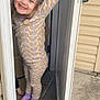 Callie is registered to the contest to win money with this photo: child, pajamas, door, door_handle, smiling, happy, girl, indoor, home, concrete_floor, socks, pigtails, patterned_clothing, footwear, playful, standing, narrow_space, wall, window, casual