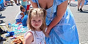 Callie is registered to the contest to win money with this photo: child, woman, princess_costume, blue_dress, red_skirt, unicorn, smile, outdoor, parade, crowd, american_flag, street, daylight, happy, people, event, young_girl, costume, celebration, public