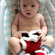 William is registered to the contest to win money with this photo: baby, child, christmas_hat, knitted_booties, baby_seat, striped_pattern, dotted_pattern, festive_clothing, infant, cute, holiday, red, white, soft_toys, portrait, indoors, sitting, curious, face, skin