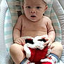 baby, child, christmas_hat, knitted_booties, baby_seat, striped_pattern, dotted_pattern, festive_clothing, infant, cute, holiday, red, white, soft_toys, portrait, indoors, sitting, curious, face, skin