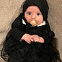 baby, infant, pacifier, black_clothing, knit_hat, sitting, couch, indoors, wide_eyes, cute, hands, portrait, child, cozy, textured_fabric, black_tutu, knitwear, expression, young_child, baby_fashion