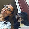 animal, black_dog, casual_clothing, companion, dog, doorway, eyewear, glasses, happy, home, indoor, long_hair, looking_up, mouth_open, people, pet, portrait, smile, white_fur, woman