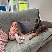Acka participe au concours pour gagner de l'argent avec cette photo : baby, dog, couch, blanket, pillow, window, indoor, smiling, pet, child, footwear, tile_floor, greenery, fence, curious, cozy, relaxing, home, light, casual