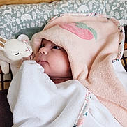 Esmée participe au concours pour gagner de l'argent avec cette photo : baby, towel, hood, plush_toy, bunny, face, infant, blanket, pattern, animal_print, cute, soft_texture, gaze, child, bed, rest, comfort, pink, white, portrait