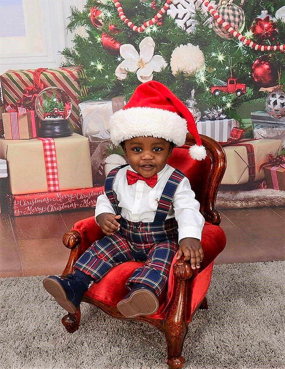 Blaise is registered to the contest to win money with this photo: christmas, christmas_decoration, christmas_ornament, headwear, holiday, person, santa_claus, toddler