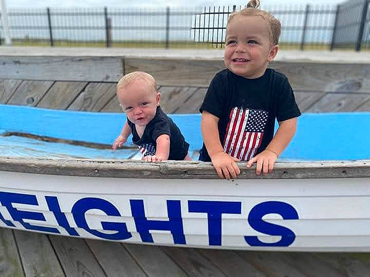 Maddox is registered to the contest to win money with this photo: baby, baby_toddler_clothing, boats_and_boating_equipment_and_supplies, child, face, font, fun, happy, joy, leisure, person, public_event, recreation, sitting, sky, sleeve, smile, t_shirt, toddler, vacation