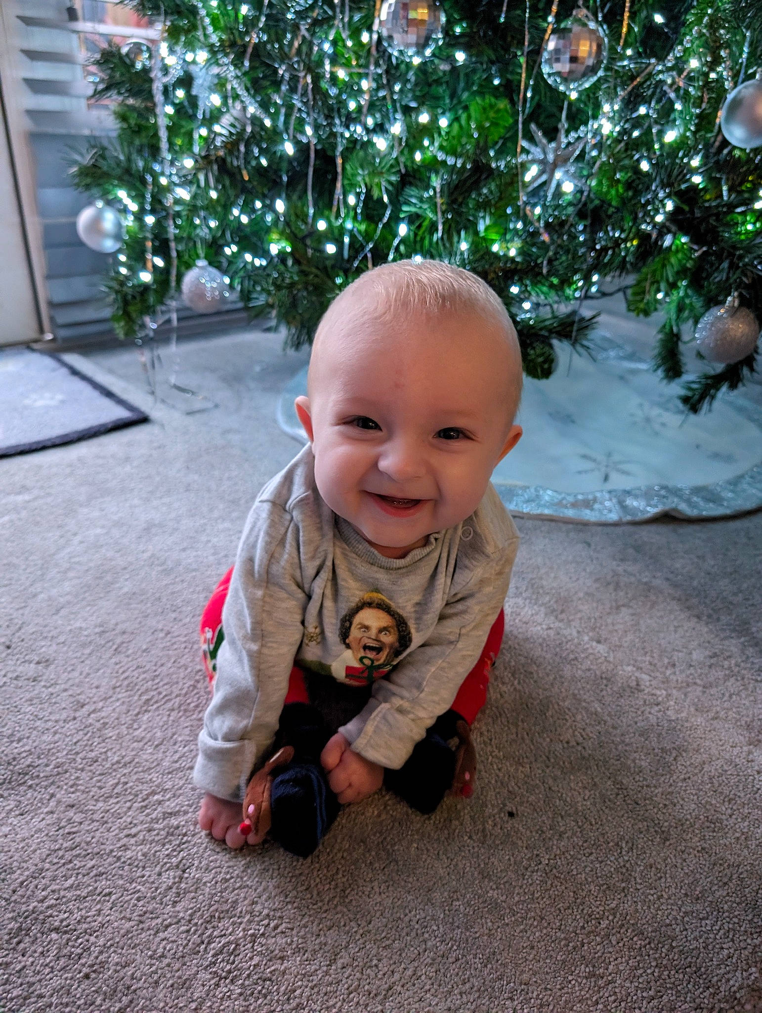 Arlo Morris is registered to the contest to win money with this photo: baby, baby_toddler_clothing, child, christmas, christmas_decoration, christmas_ornament, christmas_tree, event, flooring, grass, happy, holiday, holiday_ornament, joy, leaf, ornament, person, plant, smile, toddler