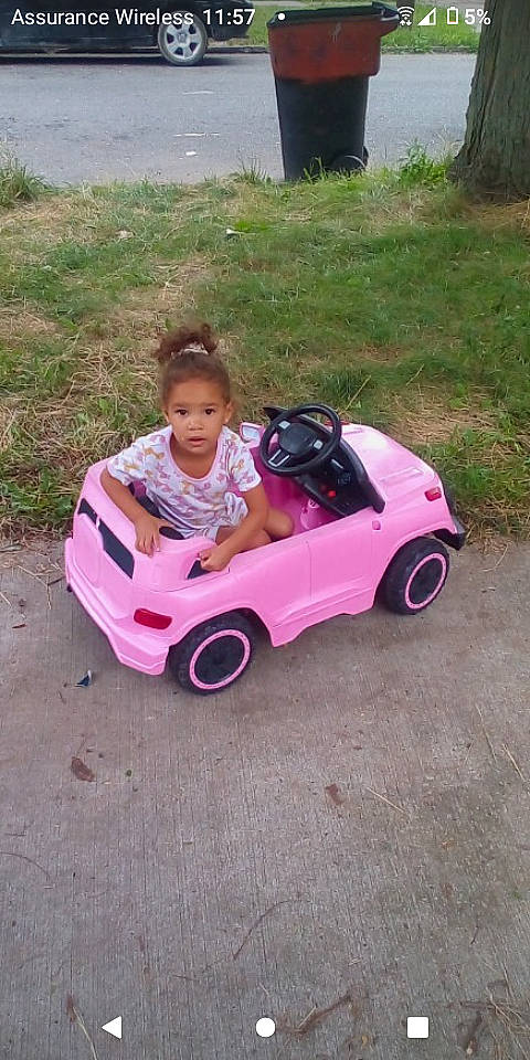 Myra is registered to the contest to win money with this photo: automotive_design, automotive_tire, automotive_wheel_system, baby_toddler_clothing, car, child, grass, magenta, motor_vehicle, person, pink, plant, recreation, riding_toy, tire, toddler, toy, tree, vehicle, wheel