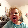 Bella is registered to the contest to win money with this photo: toddler, child, curly_hair, tongue_out, unicorn, shirt, indoor, home, photograph, playful, smiling, person, young_child, cute, happy, wall, bag, family_photos, casual_clothing, portrait
