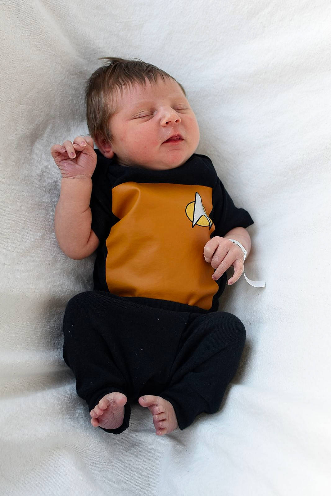 Malcolm is registered to the contest to win money with this photo: arm, baby, baby_toddler_clothing, cheek, comfort, eye, finger, flash_photography, gesture, hand, head, joint, knee, neck, outerwear, person, shoulder, skin, sleeve, t_shirt