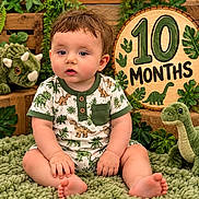 Woodsen joined the competition — help win amazing prizes! baby, infant, child, portrait, sitting, curious, face, eyes, smiling, dinosaur, stuffed_animal, plush_toy, milestone, ten_months, wooden_sign, jungle_theme, tropical_leaves, greenery, onesie, indoor